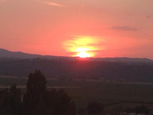 a sunset with the sun setting over a field at Sunnyhill Home in Monterotondo
