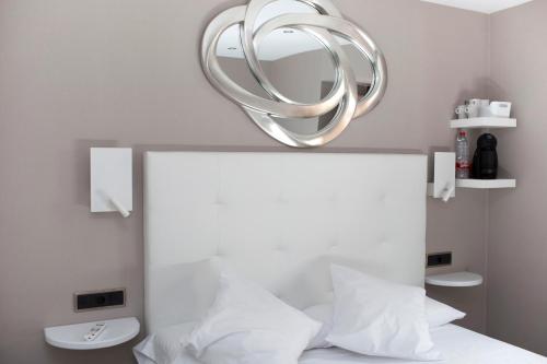 a circular mirror above a bed with white pillows at La Sepia Boba (Adults only) in Peñíscola