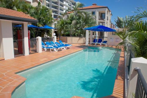 a large swimming pool with blue chairs and umbrellas at Chevron Palms in Gold Coast