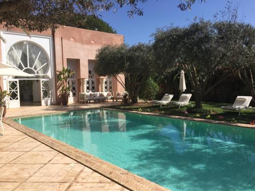 a swimming pool with chairs and a building at Riad des Golfs in Agadir