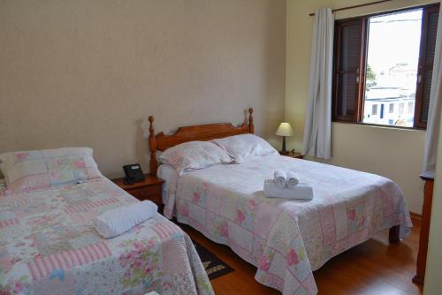 a bedroom with two beds and a window at Hotel Real São Lourenço in São Lourenço
