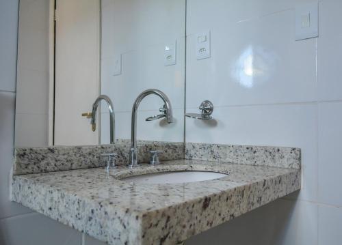 a bathroom counter with a sink and a mirror at Hotel Real São Lourenço in São Lourenço