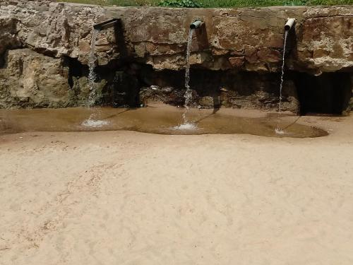 a stream of water coming out of a stone wall at Casa Larithur in Beberibe