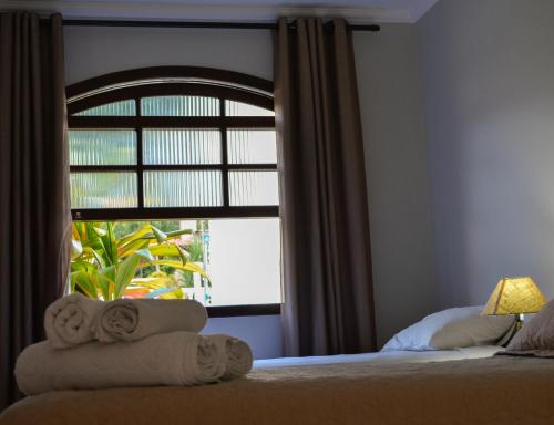 a bedroom with a window with towels on a bed at Hotel Real São Lourenço in São Lourenço