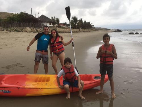 a group of people standing next to a kayak on the beach at Baja Canoas Hotel in Canoas De Punta Sal