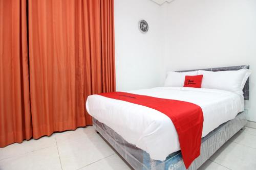 a bedroom with a bed with a red blanket at RedDoorz Plus @ Affandi Gejayan in Yogyakarta