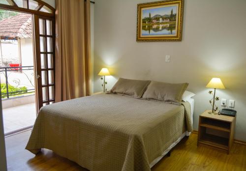 a bedroom with a bed and a door to a balcony at Hotel Real São Lourenço in São Lourenço