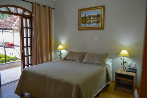 a bedroom with a bed and a door to a balcony at Hotel Real São Lourenço in São Lourenço