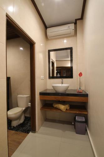uma casa de banho com um lavatório, um WC e um espelho. em Yuni's House em Ubud