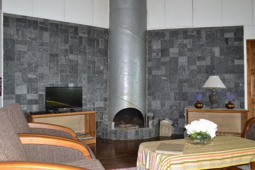 a living room with a fireplace with a table and a television at Mesilau Mountain Retreats in Kundasang