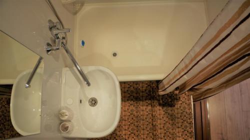 a bathroom with a white tub and a sink at "GOOD NIGHT" on Pirogova 7 in Tomsk