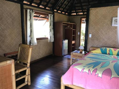 a bedroom with a bed and a chair and a window at Pension Motu Iti in Pihaena