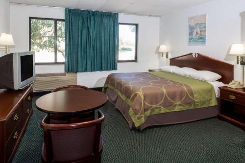 a hotel room with a bed and a flat screen tv at Super 8 by Wyndham Pompano Beach in Pompano Beach