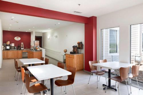 a dining room with two tables and a kitchen at Super 8 by Wyndham Garland Rowlett East Dallas Area in Garland