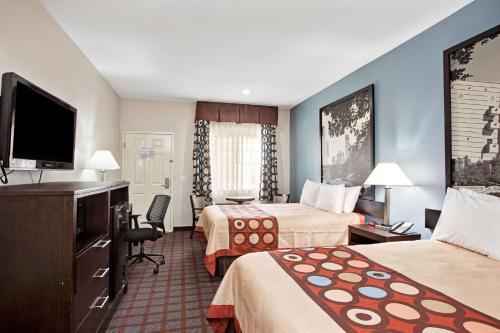 a hotel room with two beds and a flat screen tv at Super 8 by Wyndham Houston North I-45 in Houston