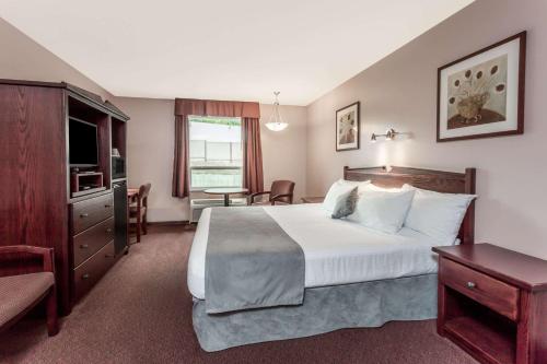 a hotel room with a large bed and a table at Super 8 by Wyndham Lake Country/Winfield Area in Winfield