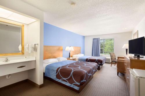 a hotel room with two beds and a television at Super 8 by Wyndham Garland Rowlett East Dallas Area in Garland