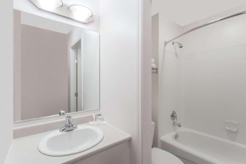 Baño blanco con lavabo y espejo en Super 8 by Wyndham Lake Country/Winfield Area, en Winfield