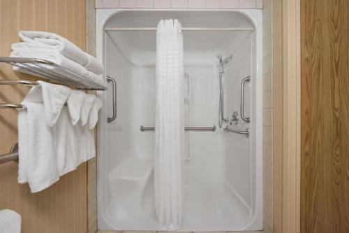 y baño con ducha y toallas blancas. en Super 8 by Wyndham Fort St. John BC, en Fort Saint John