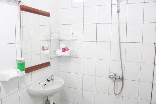 ein weißes Bad mit einem Waschbecken und einer Dusche in der Unterkunft JS Guest House in Seminyak