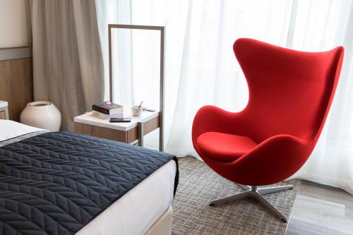 a red chair sitting in a bedroom next to a bed at HOTEL THE FLAG Shinsaibashi in Osaka