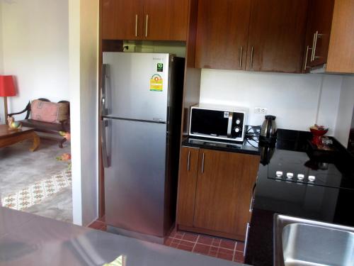 a kitchen with a refrigerator and a microwave at Jasmine Hills Lodge in Doi Saket