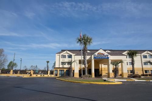 a hotel building with a palm tree in front of it at Baymont by Wyndham Saraland in Saraland