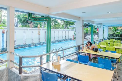 a woman sitting at a table in front of a swimming pool at New Siam II in Bangkok
