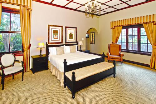 
a hotel room with a bed, chair, table and window at Audacia Manor Boutique Hotel in Durban
