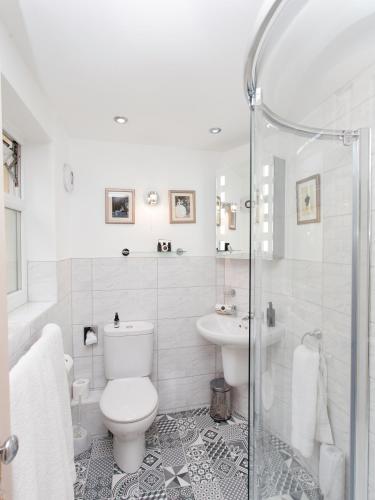 a white bathroom with a toilet and a sink at The Somerville in Torquay