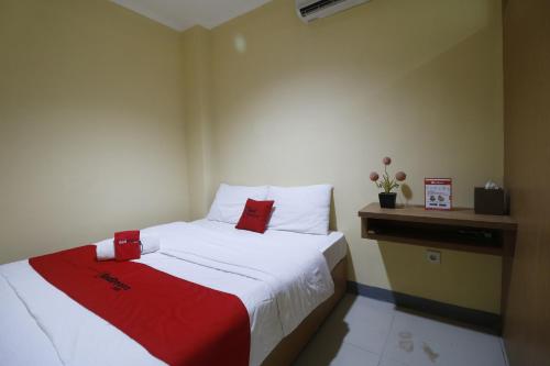 een kleine slaapkamer met een bed met een rode deken bij RedDoorz near ITC Cempaka Mas in Jakarta