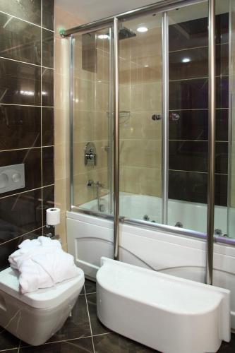 a bathroom with a shower and a toilet and a tub at Hotel Senbayrak City in Adana