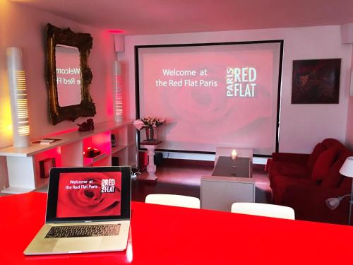 a laptop on a red table in a room with a screen at Red Flat Paris in Paris