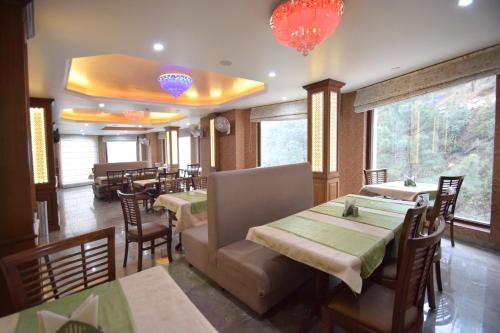a restaurant with tables and chairs and chandeliers at Rock Castle By DLS Hotels in Shimla