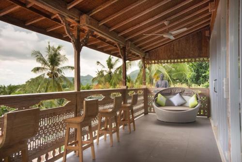 a porch with chairs and a tub on a balcony at Bella Kita Mountain Retreat & Spa in Klungkung