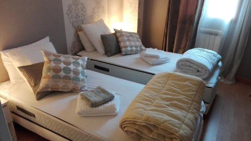 une chambre avec deux lits avec des oreillers dessus dans l'établissement Maison le Napoléon 3 chambres 7 lits, à Saint-Leu-la-Forêt