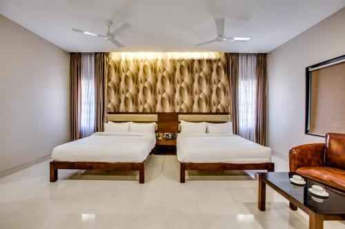 a hotel room with two beds and a couch at Hotel Ma Grand in Pudukkottai