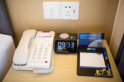 a desk with a phone and an alarm clock at Holiday Inn Express Emei Mountain by IHG in Emeishan