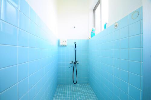 Łazienka z prysznicem wyłożona jest niebieskimi kafelkami. w obiekcie Pension Yonaha Dake w mieście Kunigami