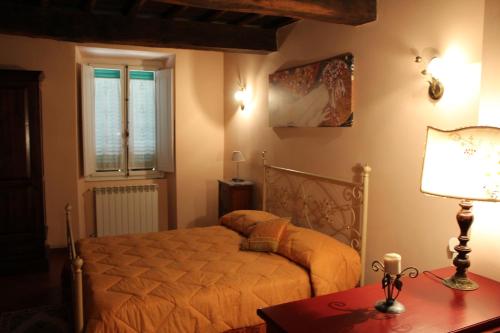 a bedroom with a bed and a table with a lamp at La Fiera Vecchia Apartments in Meleto