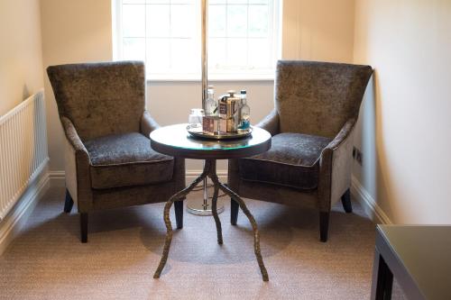 two chairs and a table in a room at Hogarths Stone Manor in Kidderminster