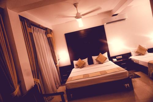 a hotel room with two beds and a window at Lavendish Okrin Hotel in Kataragama