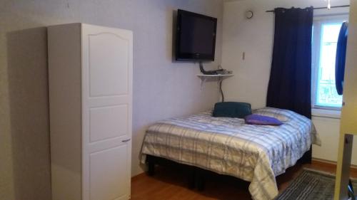 a small bedroom with a bed and a tv on the wall at Cosy studio apartment in Vaasa