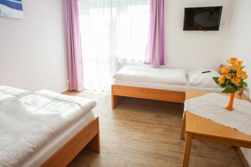 a bedroom with two beds and a vase of flowers on a table at Vila Sofia in Luhačovice