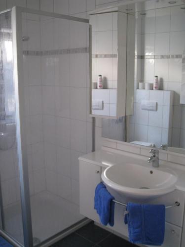 a white bathroom with a sink and a shower at Reiger Ferienwohnungen in Wackersdorf