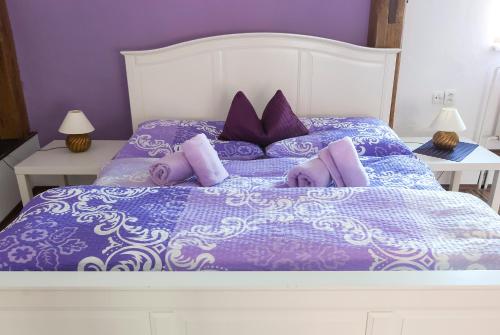 a purple bed with purple and white sheets and pillows at Fontana Pizzeria - Pension in České Budějovice