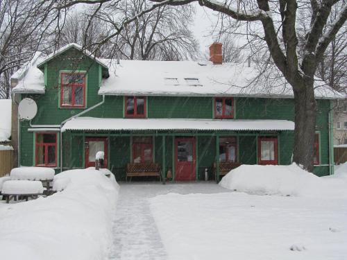 a green house with red doors in the snow at Raibie Logi in Ventspils
