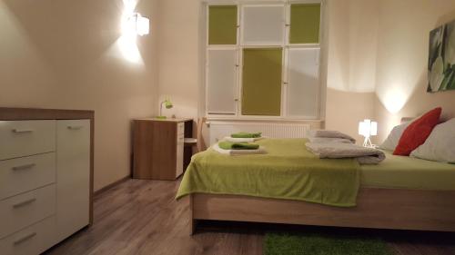 a bedroom with a bed with green sheets and a dresser at Apartament w Starej Kamienicy in Poznań