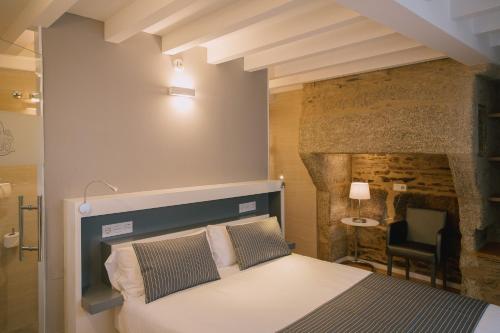 1 dormitorio con 1 cama frente a una pared de piedra en Os Sobriños Do Pai, en Santiago de Compostela