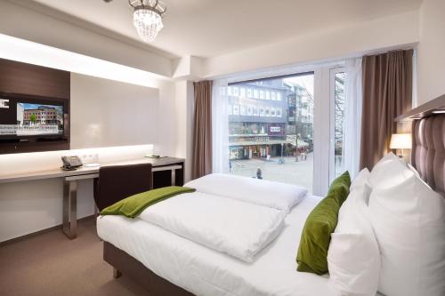 a hotel room with a bed and a desk and a window at Bergmann Boardinghouse Osnabrück in Osnabrück